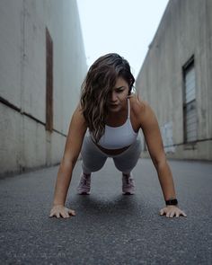 a woman is doing push ups in the middle of an alley way with no shoes on