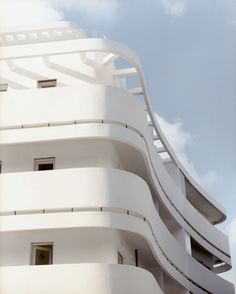 a tall white building with many balconies on it's sides and windows