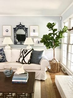 a living room filled with white furniture and lots of pillows on top of it's couches