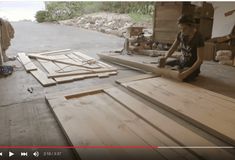 a man sitting on the floor working on some wooden planks in a garage area