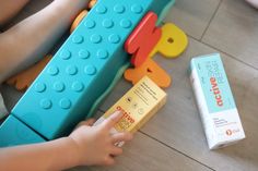 a child is playing with toys on the floor next to a tube of toothpaste