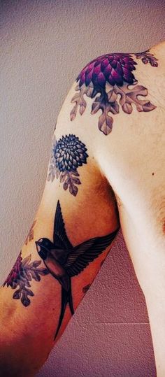 a man with a tattoo on his arm has a flower and bird design on it