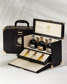 an open black box containing three bottles of liquor and two empty ones with gold trimmings