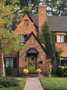 a brick house with green front door surrounded by trees