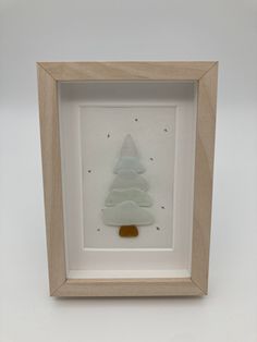 a glass christmas tree in a wooden frame on a white surface with stars around it