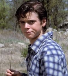 a young man is standing in the woods