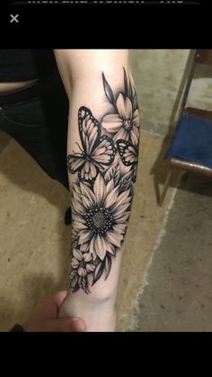 a woman's arm with flowers and butterflies tattooed on the arm, in black and white