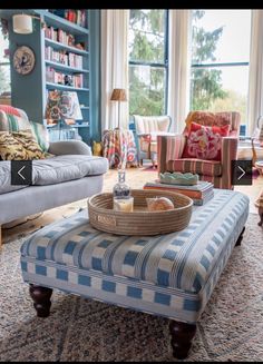 a living room with couches, chairs and a coffee table in front of two windows