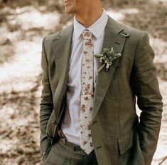 a man wearing a suit and tie standing in the woods