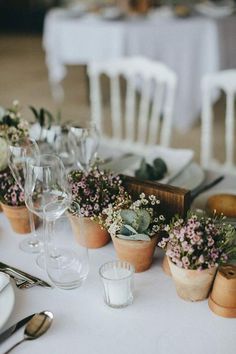 the table is set with flowers and wine glasses for guests to sit down at their place settings