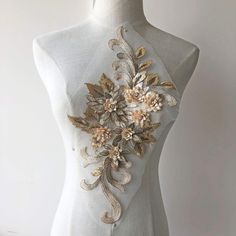 a white mannequin with gold flowers on it's chest and back side