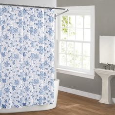 a shower curtain with blue flowers on it in front of a white sink and window