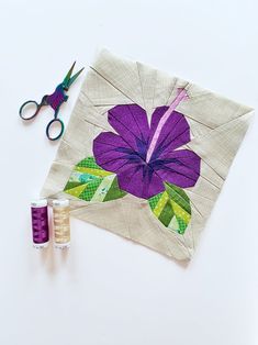 a pair of scissors and thread next to a piece of fabric with a flower on it