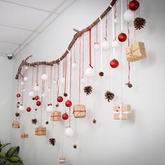 christmas decorations hanging from a tree branch on the wall