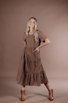 Indulge in the sophistication of the Taryn Gingham Dress on Brown. Made from 100% cotton, this midi dress boasts a modest silhouette and timeless gingham print, making it the perfect fall dress. Elevate your wardrobe with this premium piece that exudes elegance and style. 100 Cotton Model Measurements: Hips 36” Waist 25” Bust: 31”, Height 5’5.5, wearing a size small Winter Dress Fashion, Casual Christmas Dress, Winter Dresses Long, Womens Plaid Christmas Dress, Gingham Dress Pattern, Cottagecore Fall Fashion, Fall Dress Pattern, Homemaker Dresses, Brown Gingham Dress