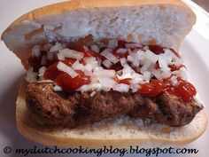 a sandwich with meat, onions and ketchup on a bun sitting on a plate