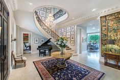 a grand piano sits in the center of this foyer with an ornate chandelier