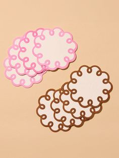 two pink and one white donut shaped stickers on a beige background with brown lines