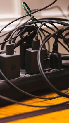 many wires and plugs are connected to each other on a table with a yellow surface