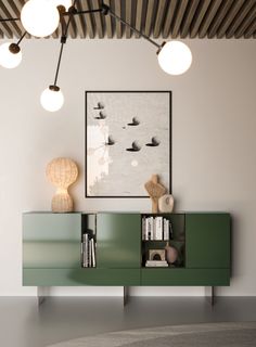 a green cabinet with some books on top of it next to a painting and lamps