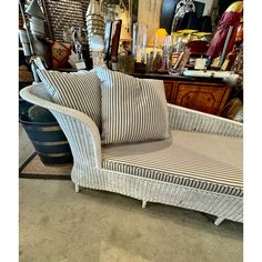 a white wicker chair with two pillows on it in front of a store display