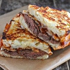 two grilled sandwiches sitting on top of a piece of parchment paper next to each other