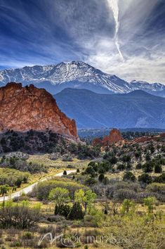 the mountains are covered in snow and clouds as seen from garden of the gods, colorado