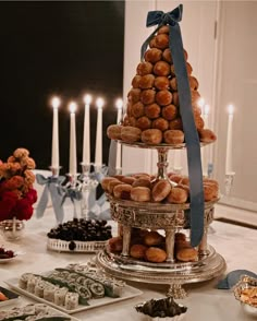 a tower of donuts sitting on top of a table next to candles and plates