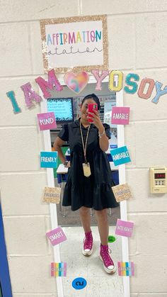 a woman taking a selfie in front of a classroom door decorated with magnets