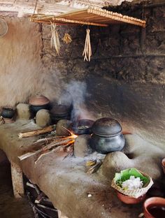 an old kitchen with pots and pans cooking on the stove top in front of it