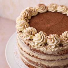 a chocolate cake with white frosting and sprinkles on top is sitting on a plate