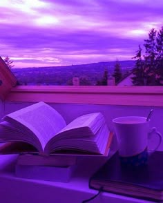 an open book sitting on top of a table next to a cup