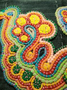 an embroidered piece with colorful designs on it's sides and some beads in the middle