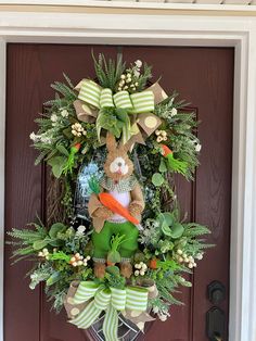 a wreath on the front door with a bunny holding an orange carrot in its mouth