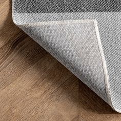 a close up view of a rug on the floor with wood grains and grey tones