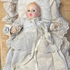 a baby doll laying on top of a white bed covered in blankets and laces