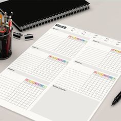 a planner with pens, pencils and other office supplies next to it on a table