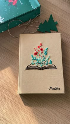 an open book sitting on top of a wooden table next to a christmas tree decoration