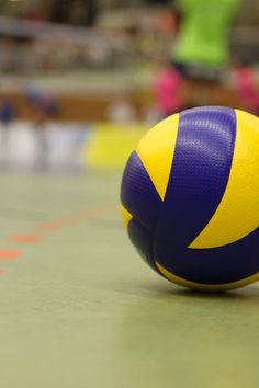 a blue and yellow volleyball sitting on the ground