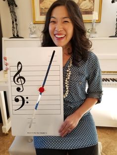 a woman holding up a piece of paper with musical notes on it and a pen sticking out of it