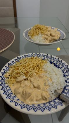 two plates filled with rice and meat covered in sauces on top of a glass table