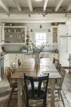 a table with chairs and a vase on it in the middle of a large kitchen