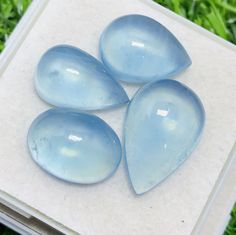 four blue glass pieces sitting on top of a white tile slab in the green grass