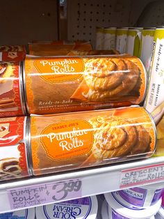 three rolls are stacked on top of each other in a store display case, with orange and white labels reading pumpkin rolls