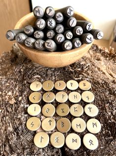 a wooden table topped with lots of different type of letters and numbers next to a bowl filled with magnets