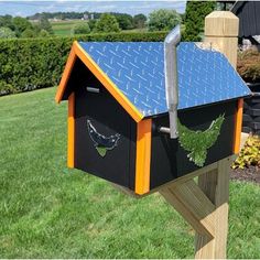 a wooden birdhouse with blue roof and green plants in the top part of it