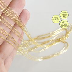 the gold chain is being held up by someone's hand with three different chains