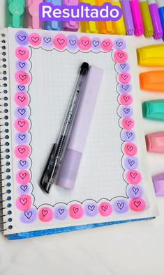 a notebook with markers and a pen on it next to some pens that are lined up in the shape of hearts