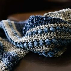 a blue and white crocheted scarf laying on top of a brown leather chair