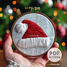 a hand holding a small embroidered christmas ornament with a santa hat on it